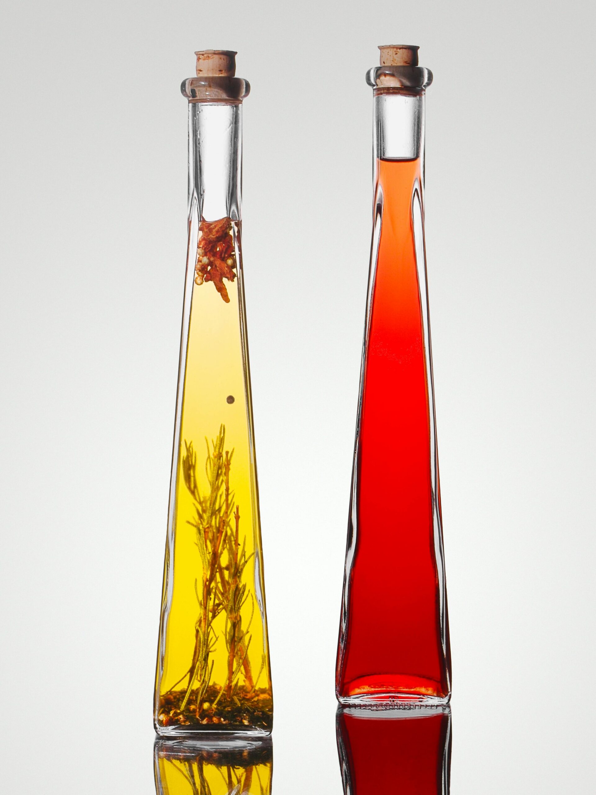 Stylish tall bottles of olive oil with herbs and red vinegar, perfect for gourmet cuisine.